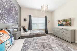 Een slaapkamer met twee bedden, een dressoir, een bureau en een groot raam met gordijnen.
