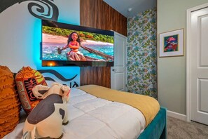 A bedroom with a bed, a TV mounted on the wall, and a door. - Themed Home w/ Pool at Storey Lake (Kissimmee)