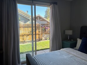 A bedroom with a bed, a nightstand, a lamp, and a view of a backyard through a sliding glass door. - Beautiful home in Antelope with private room, and private access. (Antelope)