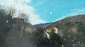 Un paysage montagneux où des bâtiments sont nichés au milieu des arbres, sous un ciel dégagé.