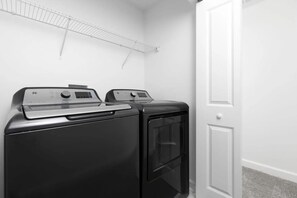 A laundry room with two stacked washers and dryers, a white door, and a metal drying rack on the wall. - Home w/ Private Pool & Mickey/star Wars Themes (Davenport)