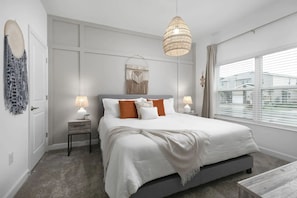 A bedroom with a large bed, two bedside tables with lamps, a hanging light fixture, a wall-mounted macrame piece, and a window with blinds. - Home w/ Private Pool & Mickey/star Wars Themes (Davenport)