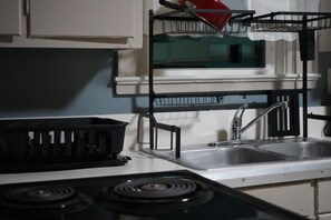 A kitchen with a double sink, a stove, and a dish rack. - Delightful 2 bedroom townhouse in Hamlet (Hamlet)