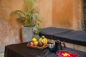 A table with a fruit tray, a coffee pot, and a bowl of flower petals. - Luxury Heritage 2 bedroom apartment with courtyard / Nyumbani Stonetown (Zanzibar)