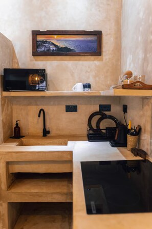 A compact kitchen with a microwave, sink, and a shelf with a framed picture. - Luxury Heritage 2 bedroom apartment with courtyard / Nyumbani Stonetown (Zanzibar)