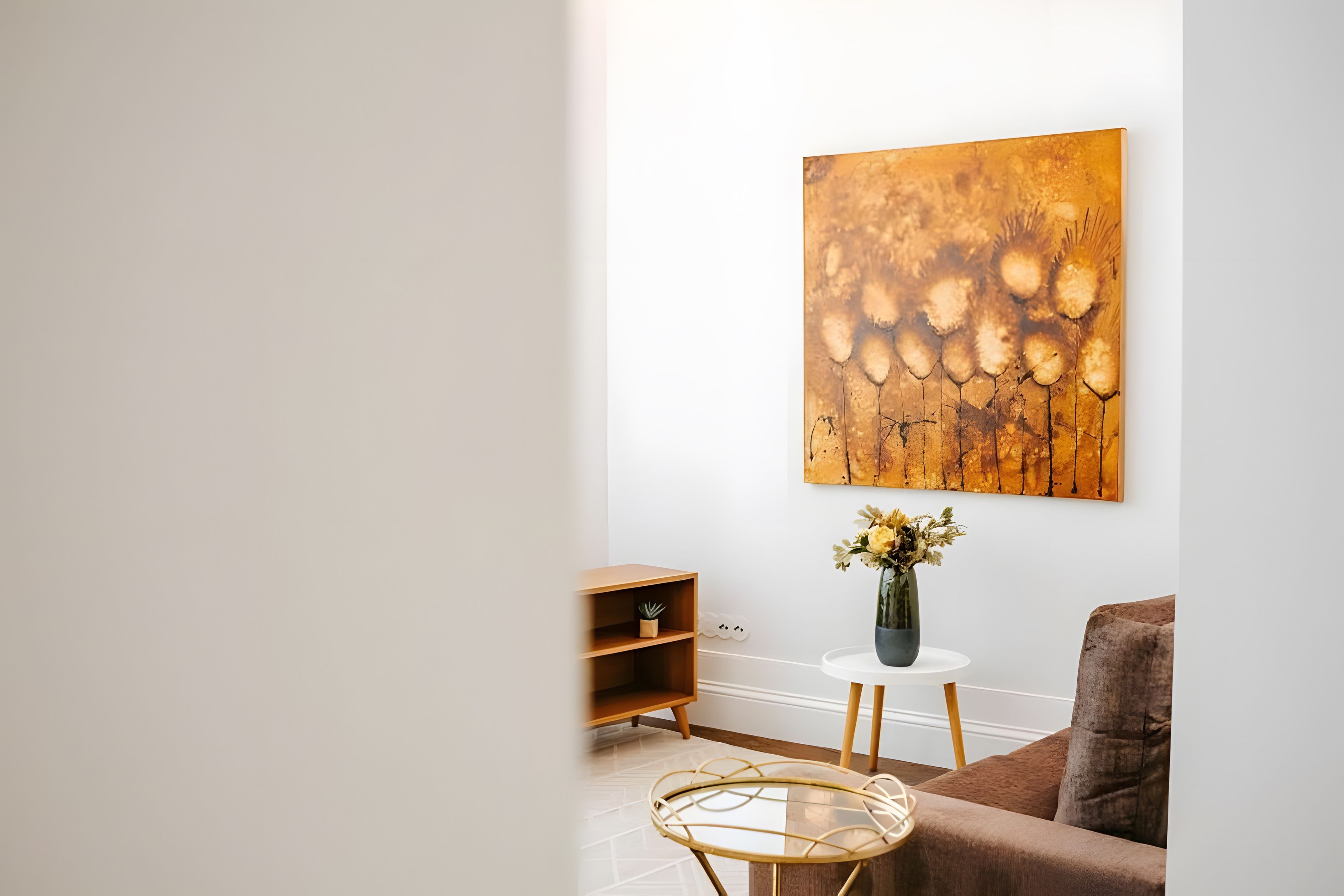 Una sala de estar moderna con un cuadro abstracto grande, una mesita redonda con un florero y un sofá marrón.