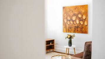 Una sala de estar moderna con un cuadro abstracto grande, una mesita redonda con un florero y un sofá marrón.