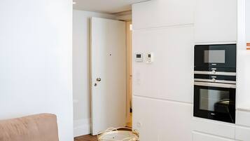 Een moderne keuken met inbouwapparatuur, een glazen tafel en een deur die naar een andere kamer leidt.
