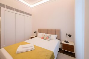 Hotellihuone, jossa on sänky, yöpöydät, vaatekaappi ja kattovalaisin.