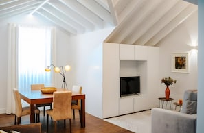 Una sala de estar moderna con comedor, televisor de pantalla plana y un cuadro en la pared.