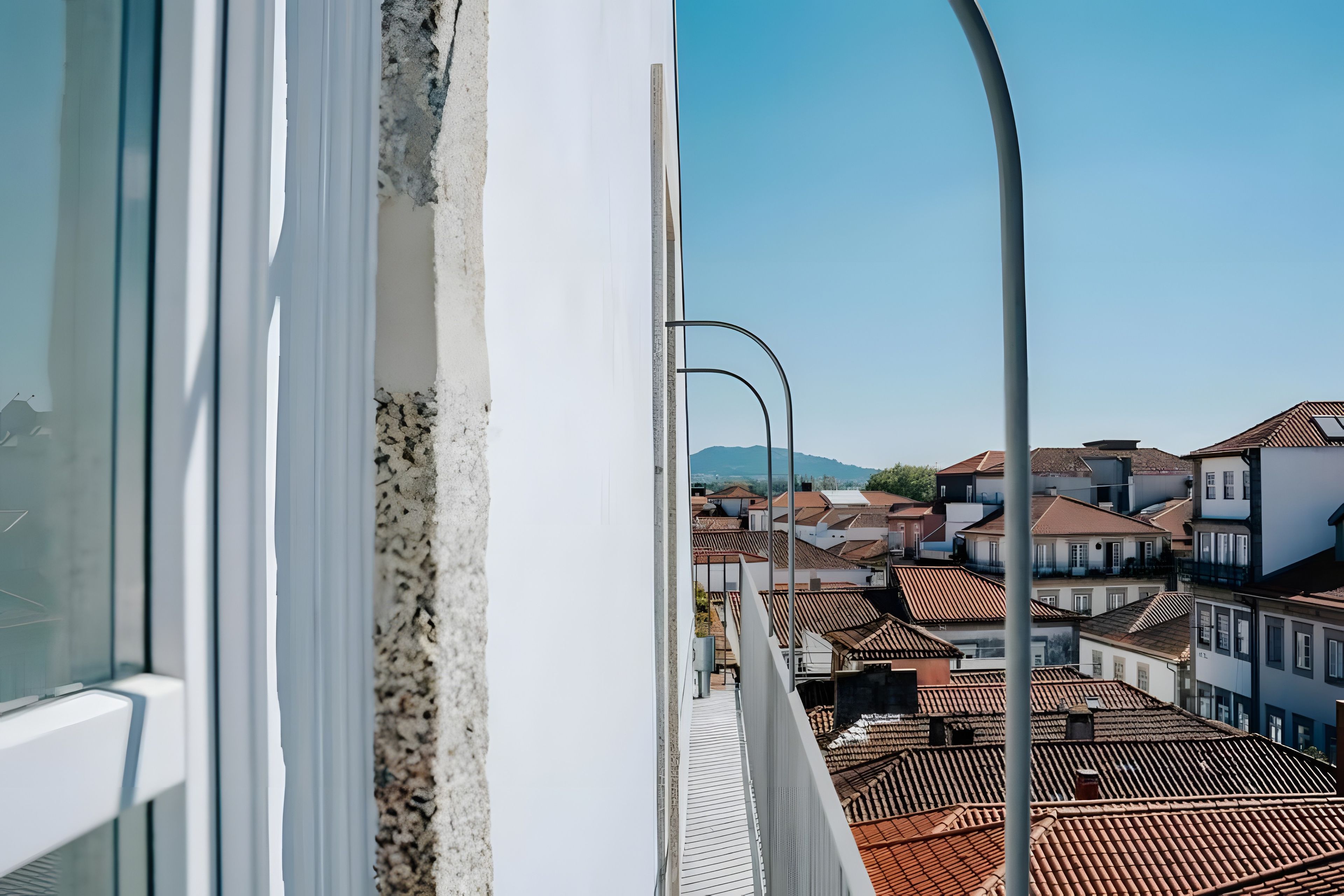 Vista desde una ventana que da a una zona residencial con tejados de baldosas tradicionales y cielo despejado.