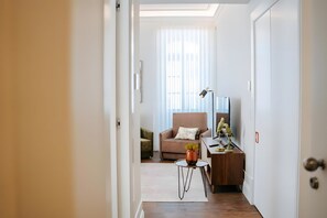 A hallway leading to a living area with a sofa, a small table with a lamp, and a decorative plant. - Apartment 'Guerreiro - T1 3A' (Viana do Castelo)
