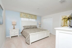A bedroom with a bed, two bedside tables, a dresser, and a window with blinds. - Private Pool Townhome Storey Lake (Kissimmee)