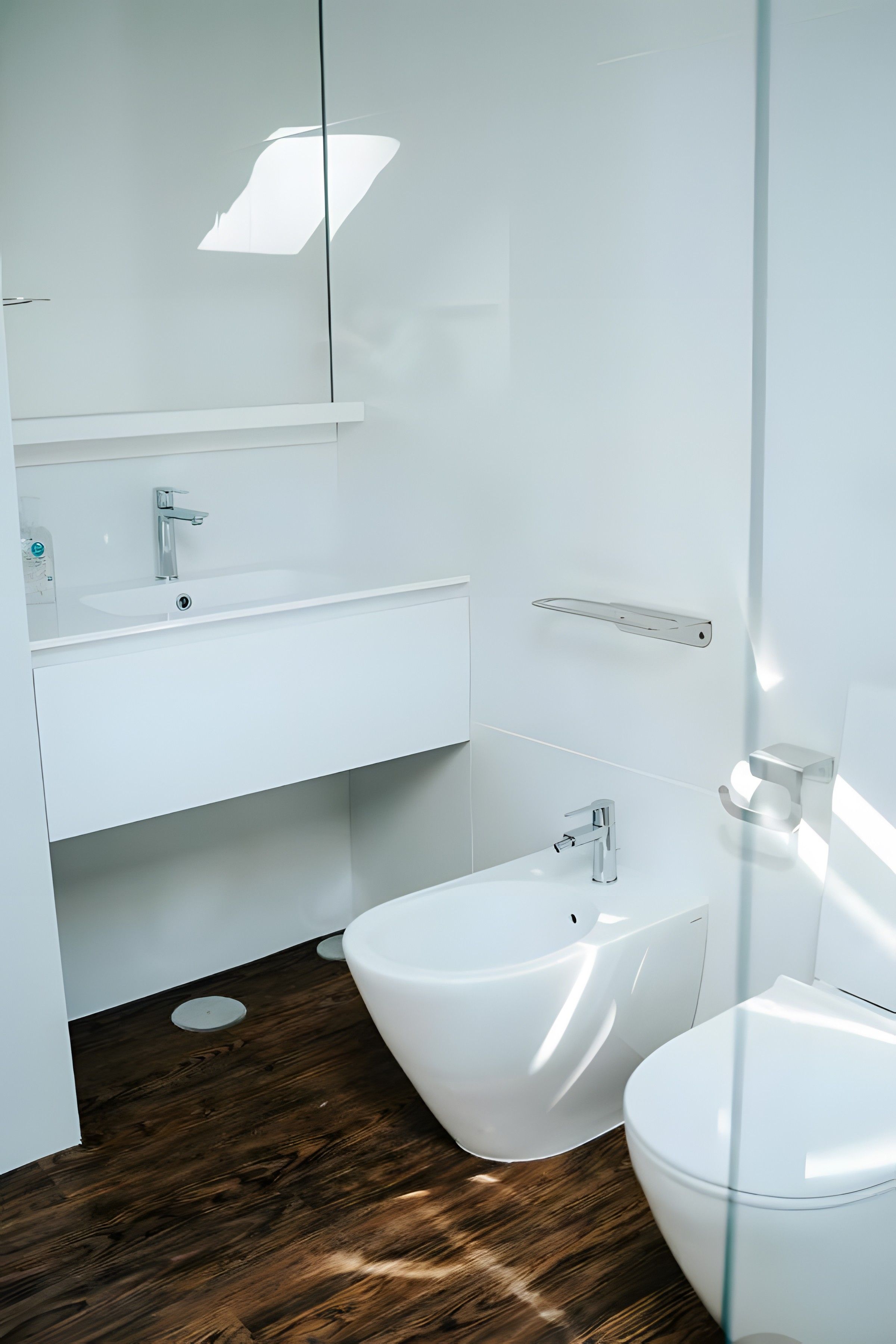 A modern bathroom with a white sink, a bidet, and a toilet.