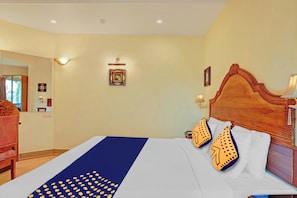 Una habitación de hotel con una cama grande, un cabecero de madera y una mesita de noche con una lámpara.