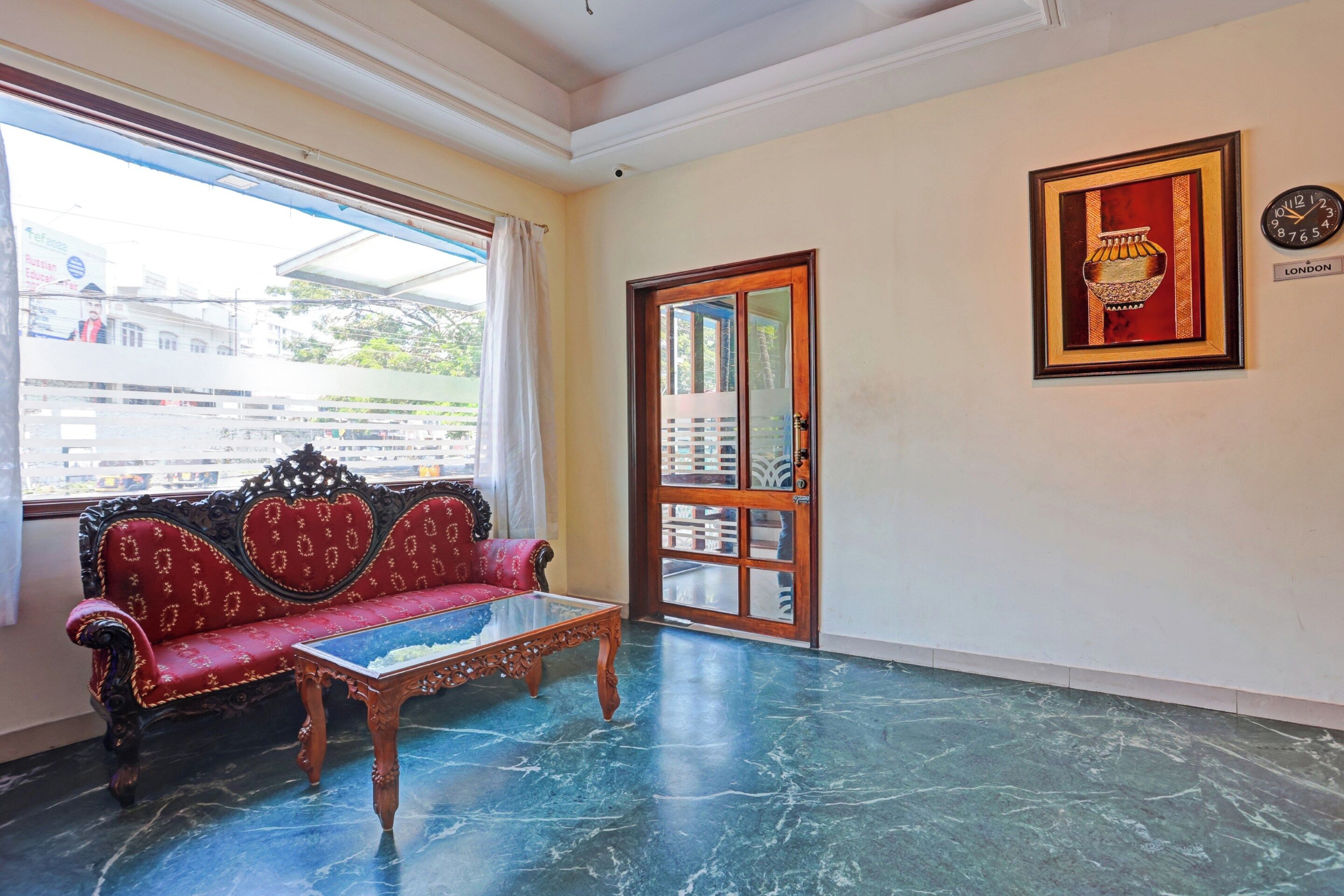 Una habitación con un sofá rojo, una mesa de centro de vidrio y una puerta con paneles de cristal.
