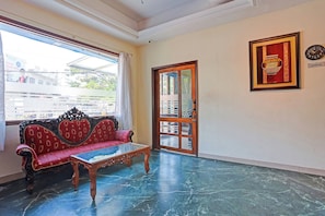 Una habitación con un sofá rojo, una mesa de centro de vidrio y una puerta con paneles de cristal.