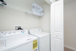 A laundry room with two white washing machines, a drying rack, and a door. - 4BR w/ Private Pool Storey Lake Resort (Kissimmee)