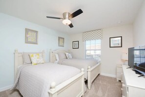A bedroom with two beds, a ceiling fan, a TV, and framed pictures on the walls. - 4BR w/ Private Pool Storey Lake Resort (Kissimmee)