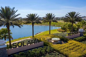 Un resort llamado SOLARA con vistas a un lago, palmeras y jardines bien cuidados.