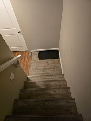 Un escalier en bois menant à un palier où se trouve un paillasson.