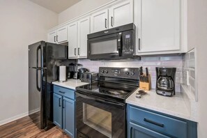 A modern kitchen with stainless steel appliances, white cabinets, and blue drawers. - 4BR Townhome W/pool Near Disney (Kissimmee)