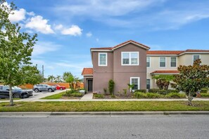 A residential building with a two-story structure, a front entrance, and a small front yard with grass and plants. - 4BR Townhome W/pool Near Disney (Kissimmee)
