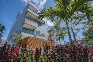A multi-story building with balconies, a wooden fence, and tropical plants. - IBIZA Ap. 109 Hernan (Ipojuca)
