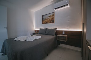 A hotel room with a bed, a nightstand, an air conditioning unit, and a wall-mounted picture. - IBIZA Ap. 109 Hernan (Ipojuca)