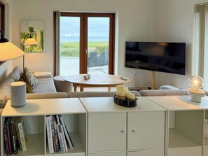 Ein Wohnzimmer mit Fernseher, Sofa, Couchtisch und Bücherregal.