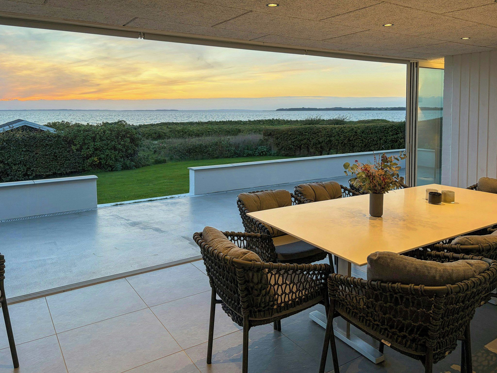 A dining area with a view of the sea, outdoor seating, and a modern design.