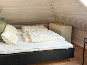 A bedroom with a bed, pillows, a nightstand, and a dresser. - Sandager Næs holiday home, beach 30 m away (Assens)