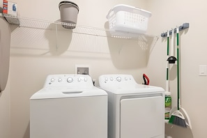 A laundry area with two white washing machines, a drying rack, a basket, and a mop. - Magical 5BR Home / Pool & Themed Rooms Near Disney (Davenport)