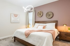 A bedroom with a bed, bedside table, lamp, and decorative wall art. - Magical 5BR Home / Pool & Themed Rooms Near Disney (Davenport)