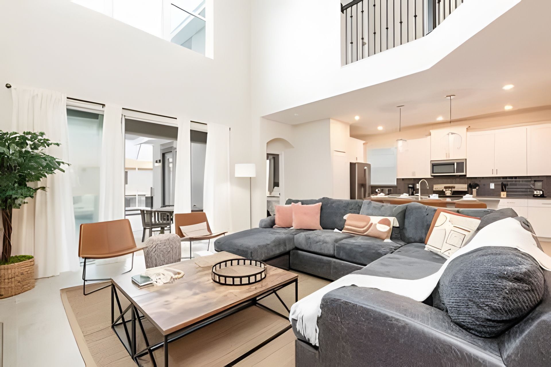 A spacious living area with a large sectional sofa, a coffee table, and a dining area with chairs.