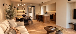A modern living room with a sofa, coffee table, and a dining area with chairs and a table. - ROI House (Athina)