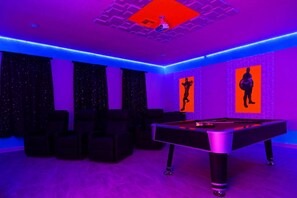 A room with a pool table, black leather chairs, and two wall-mounted screens displaying silhouettes. - 9BR Luxury Villa Storey Lake Orlando (Kissimmee)
