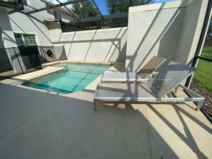 A swimming pool with two sun loungers and a covered patio area. - Your Orlando Home With Private Pool (Davenport)