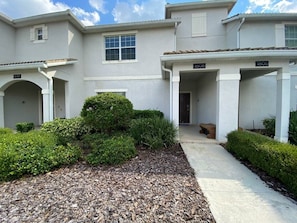 A two-story residential building with a covered driveway and a well-maintained garden area. - Your Orlando Home With Private Pool (Davenport)