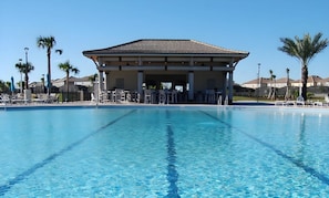 A clear blue pool with a covered seating area and palm trees in the background. - Your Orlando Home With Private Pool (Davenport)