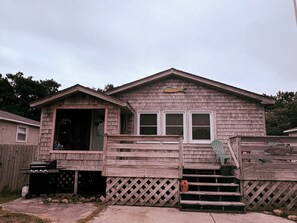 Una casa de madera con una terraza, una parrilla y una decoración de pez en la pared.