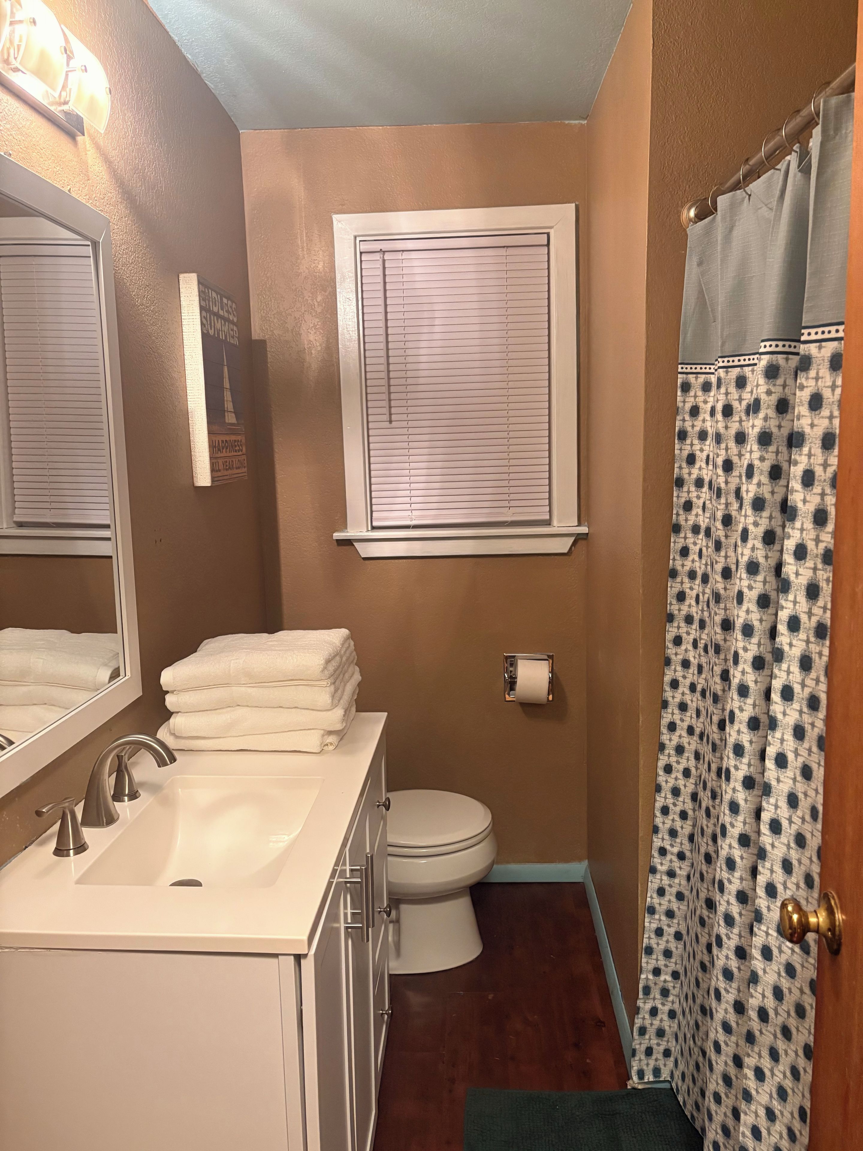 A bathroom with a sink, toilet, and window with blinds.