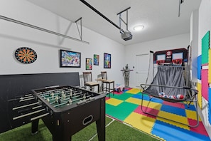 Ein Zimmer mit Kicker, Dartscheibe und einem kleinen Basketballkorb.