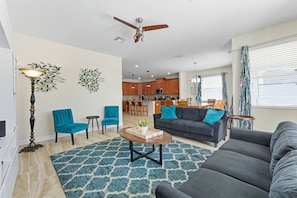 Ein Wohnzimmer mit Sofa, Sessel, Couchtisch und Deckenventilator.