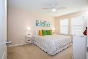 A bedroom with a bed, two bedside tables, a ceiling fan, and a window with blinds. - Compass Bay Family Comfort & Resort Amenities (Kissimmee)