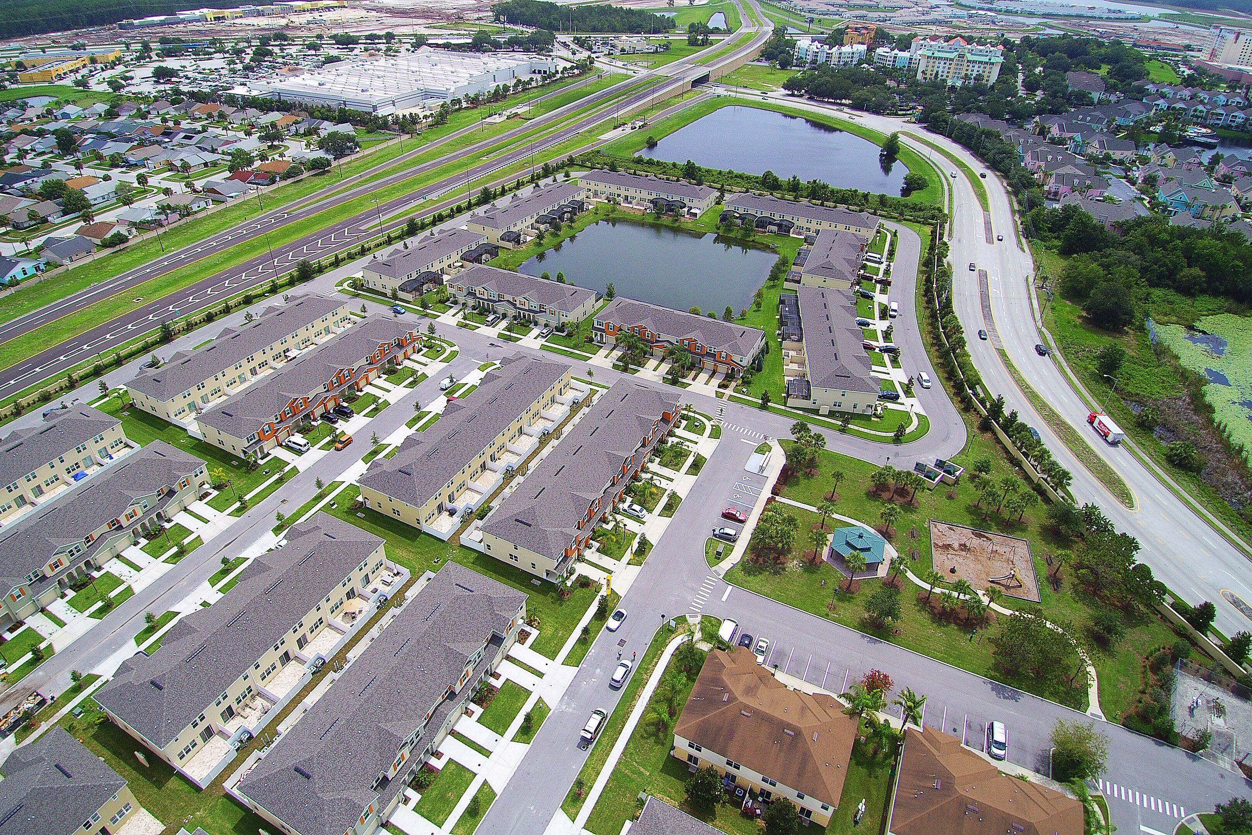 A large parking lot with multiple rows of parked cars and a central landscaped area with a pond.