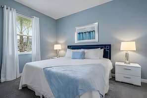 A neatly arranged bedroom with a bed, two bedside tables, a window with curtains, and a framed picture on the wall. - 8BR Villa w/ Pool, Theater & Game Room (Davenport)