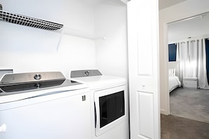 A laundry room with two white dryers and a vent above them. - Disney 4BR Home w/ Pool + Themed Bedrooms (Kissimmee)