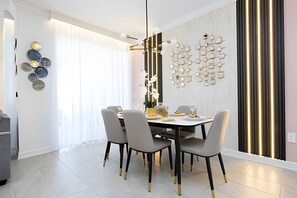 Un espace repas moderne avec une table ronde, quatre chaises et un mur décoratif orné de motifs géométriques.