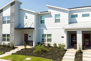 A modern multi-story residential building with a flat roof, large windows, and a well-maintained garden area. - Disney 4BR Home w/ Pool + Themed Bedrooms (Kissimmee)